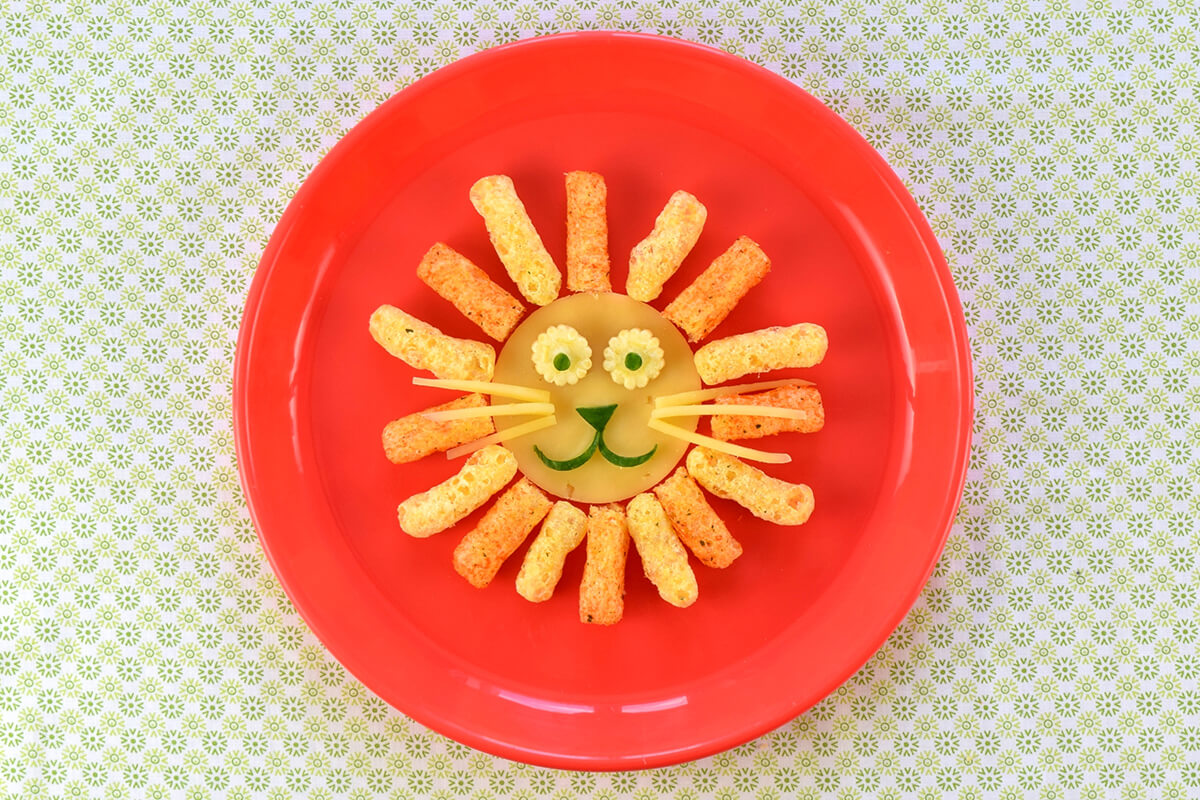 6 slivers of cheese are arranged on either side of the lion's face to create whiskers