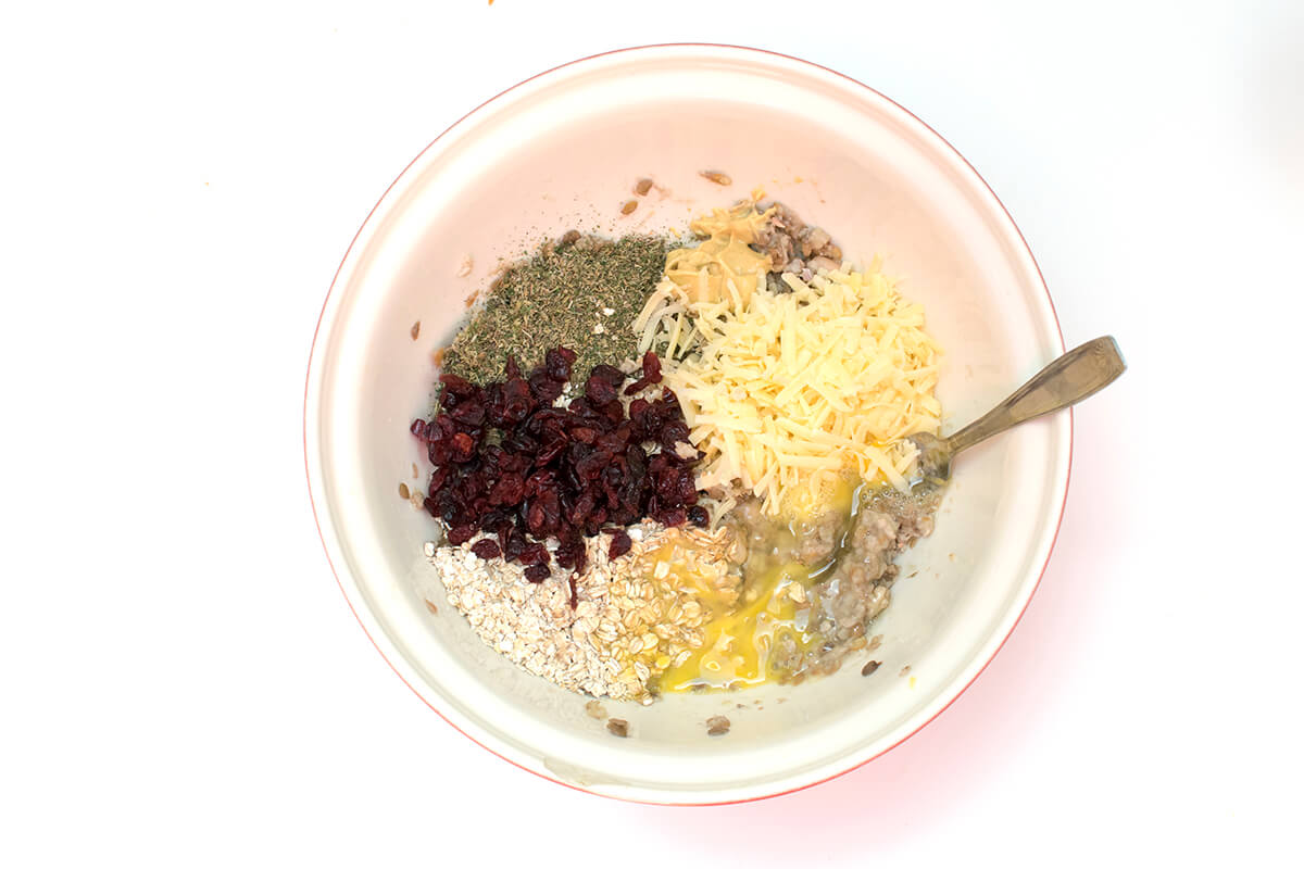 A bowl of lentils, oats, grated cheese, cranberries, dried herbs and beaten eggs
