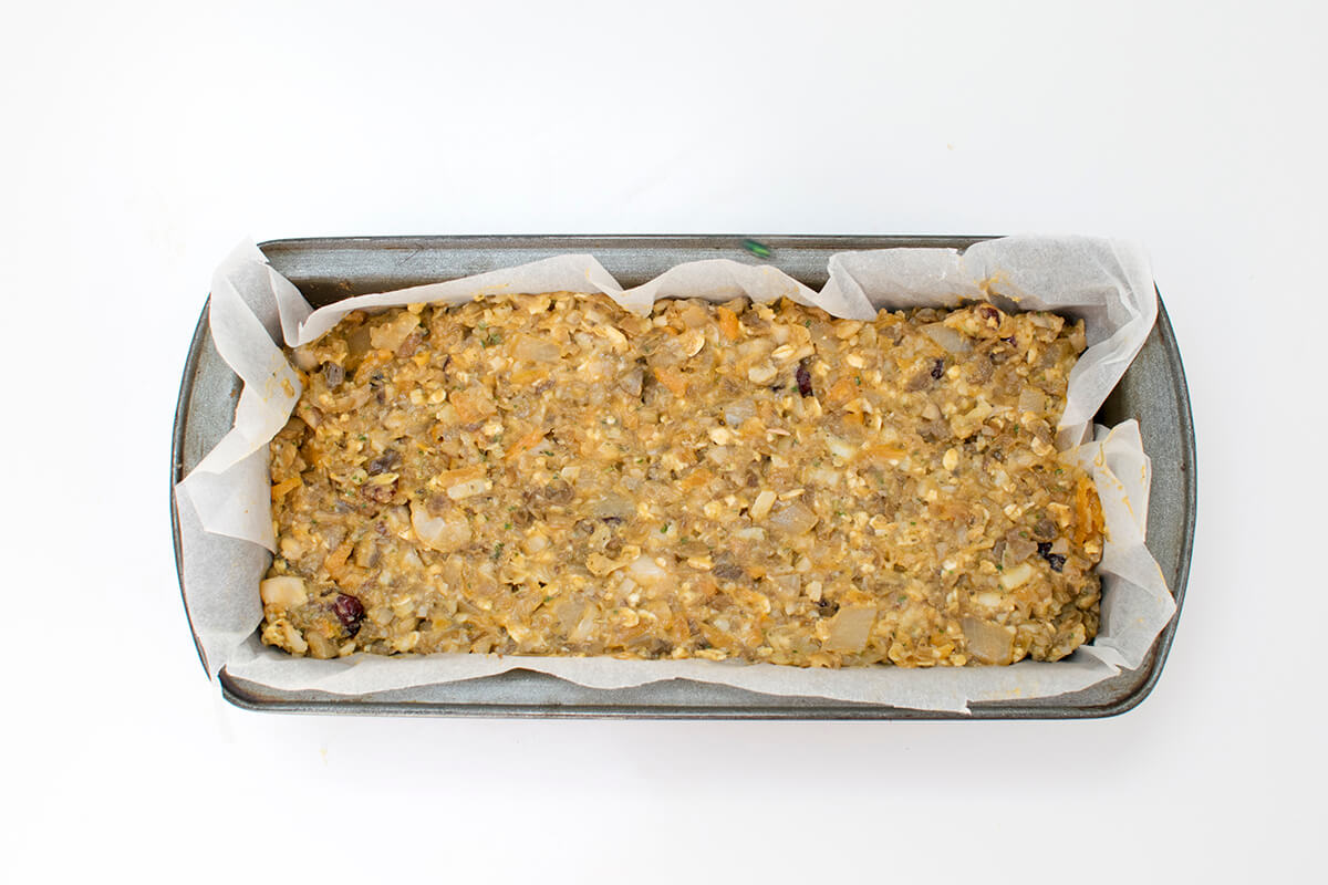 A loaf tin lined with greaseproof paper with the lentil roast mix inside it