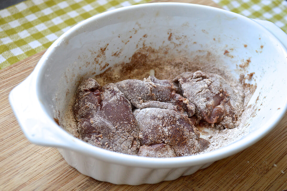 Liver being rolled in black pepper, spice and flour mix
