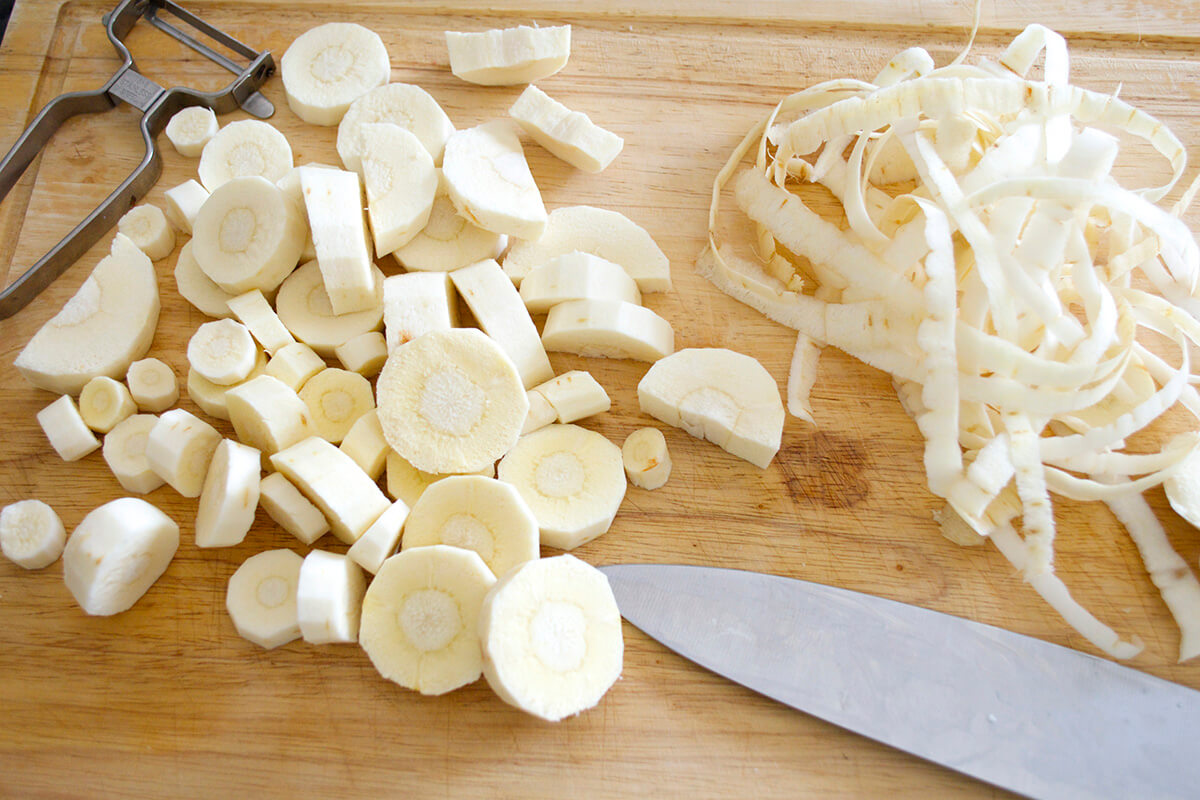A chopping board with peeled and sliced parsnips
