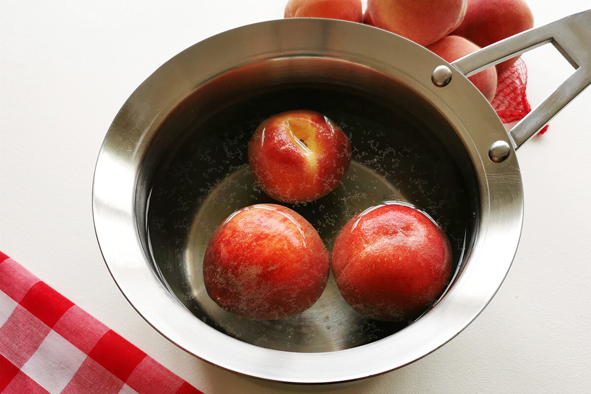 3 peaches in a saucepan of water