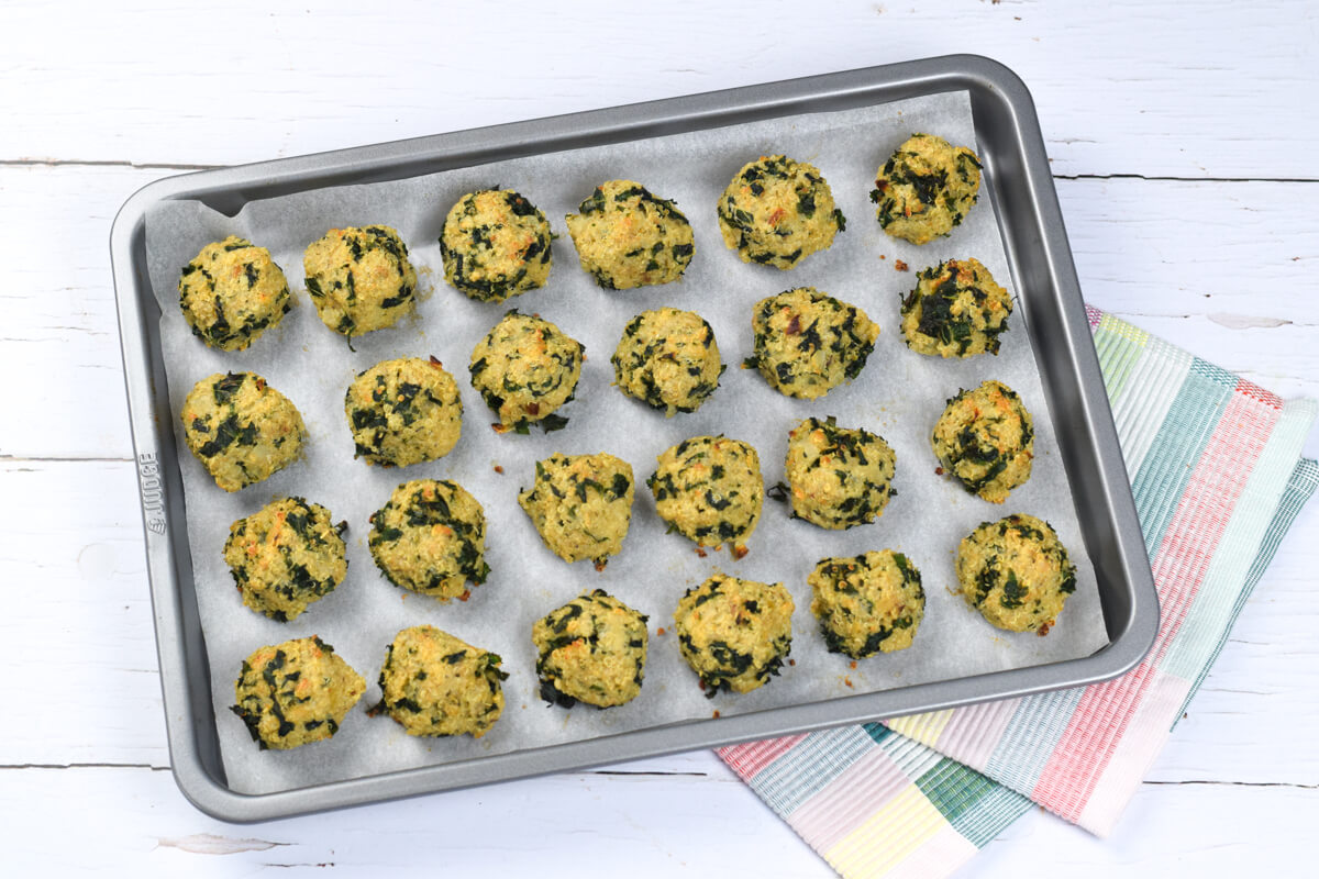 A lined baking tray with cooked quinoa and kale bites