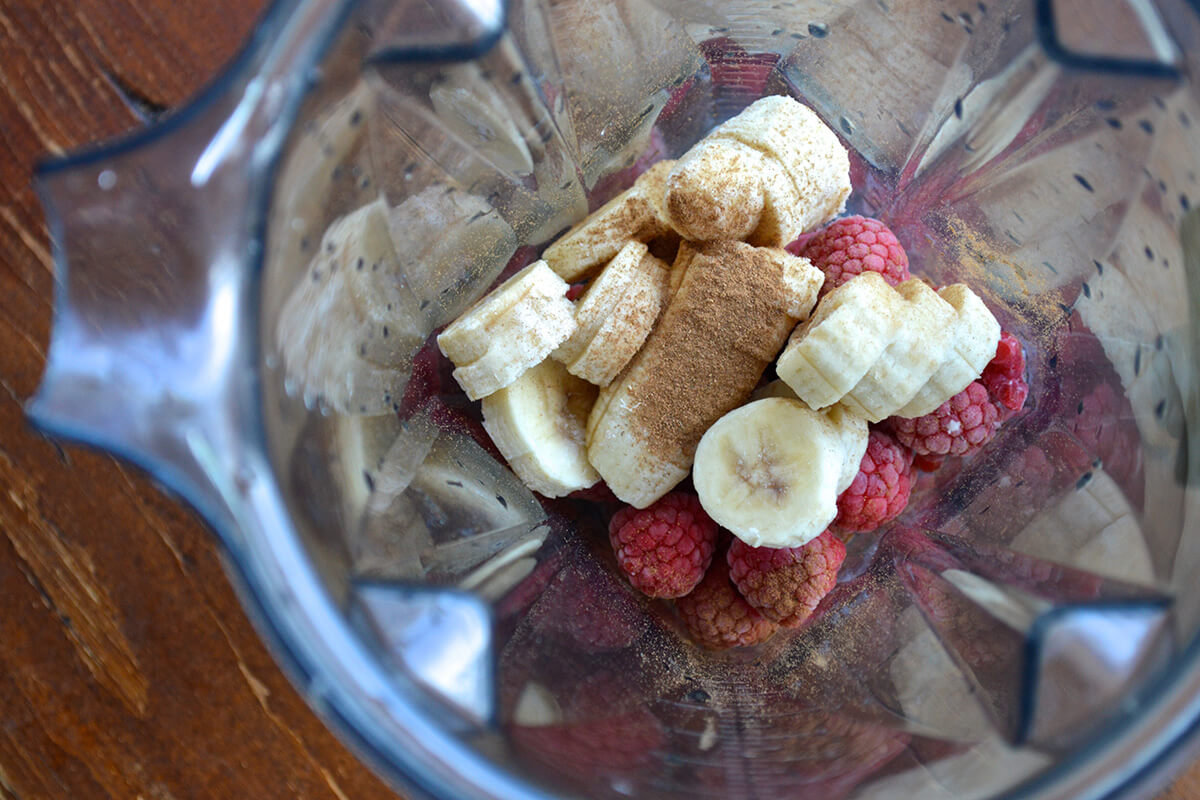 Frozen banana and raspberries in a blender with cinnamon