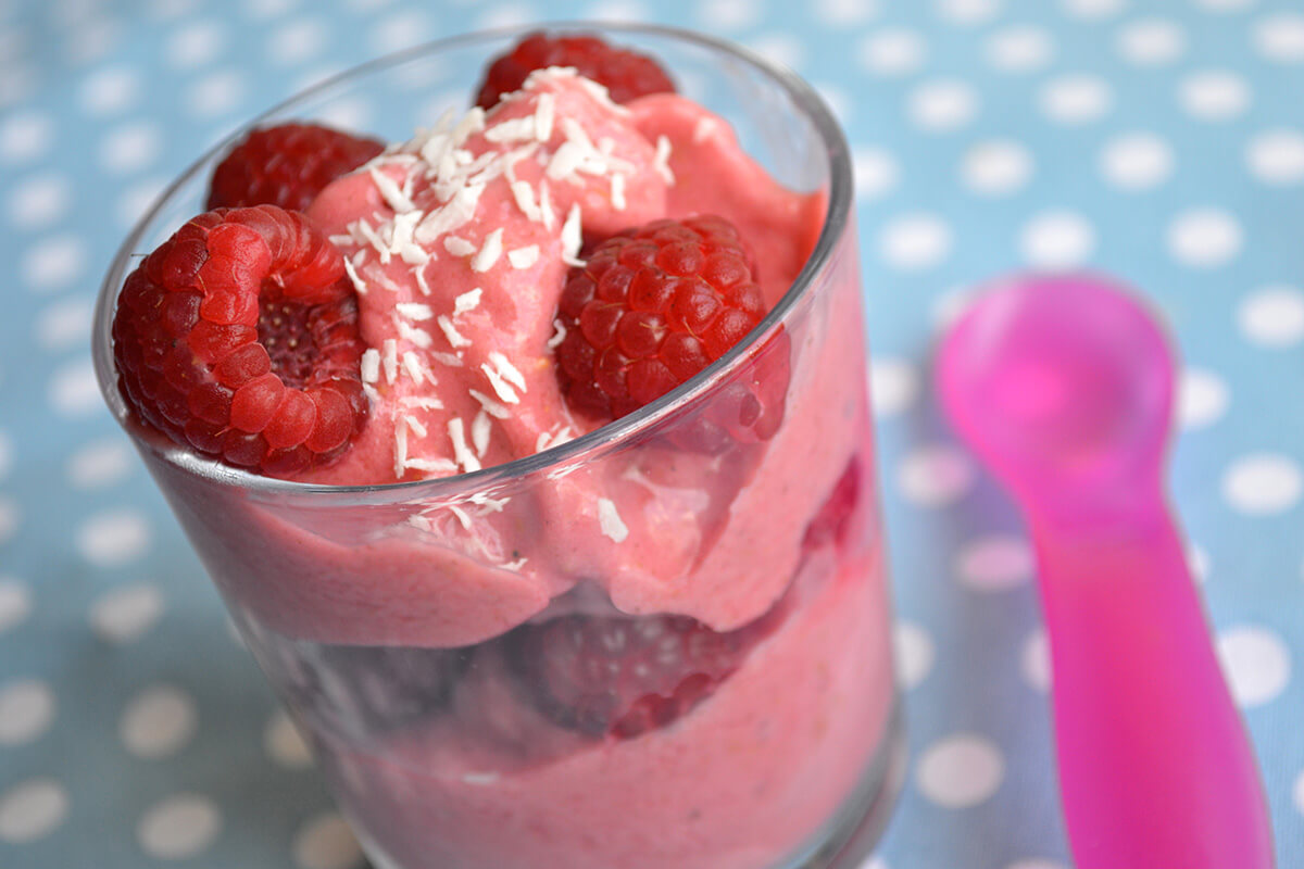 Raspberry & Banana Sundae served in a small glass with fresh raspberries and a sprinkle of desiccated coconut