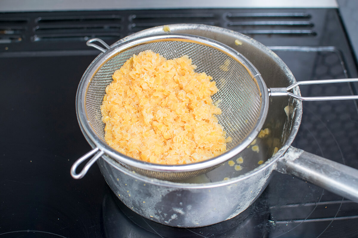 Cooked lentils being drained over a saucepan to reserve some of the cooking water