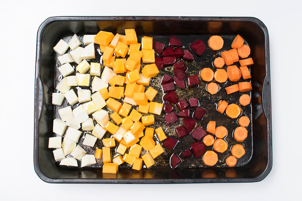 A roasting tray with diced parsnip, butternut squash, beetroot and carrot