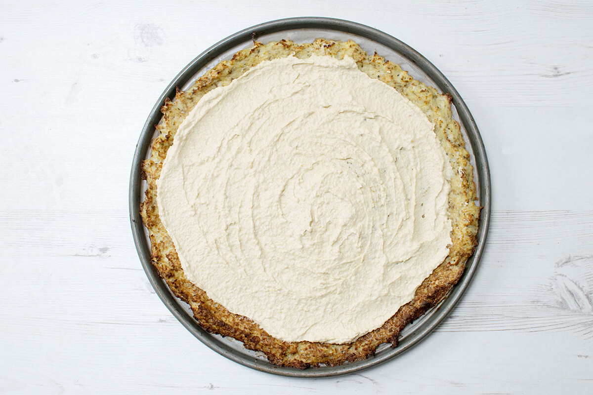 Cauliflower pizza crust with hummus spread on top