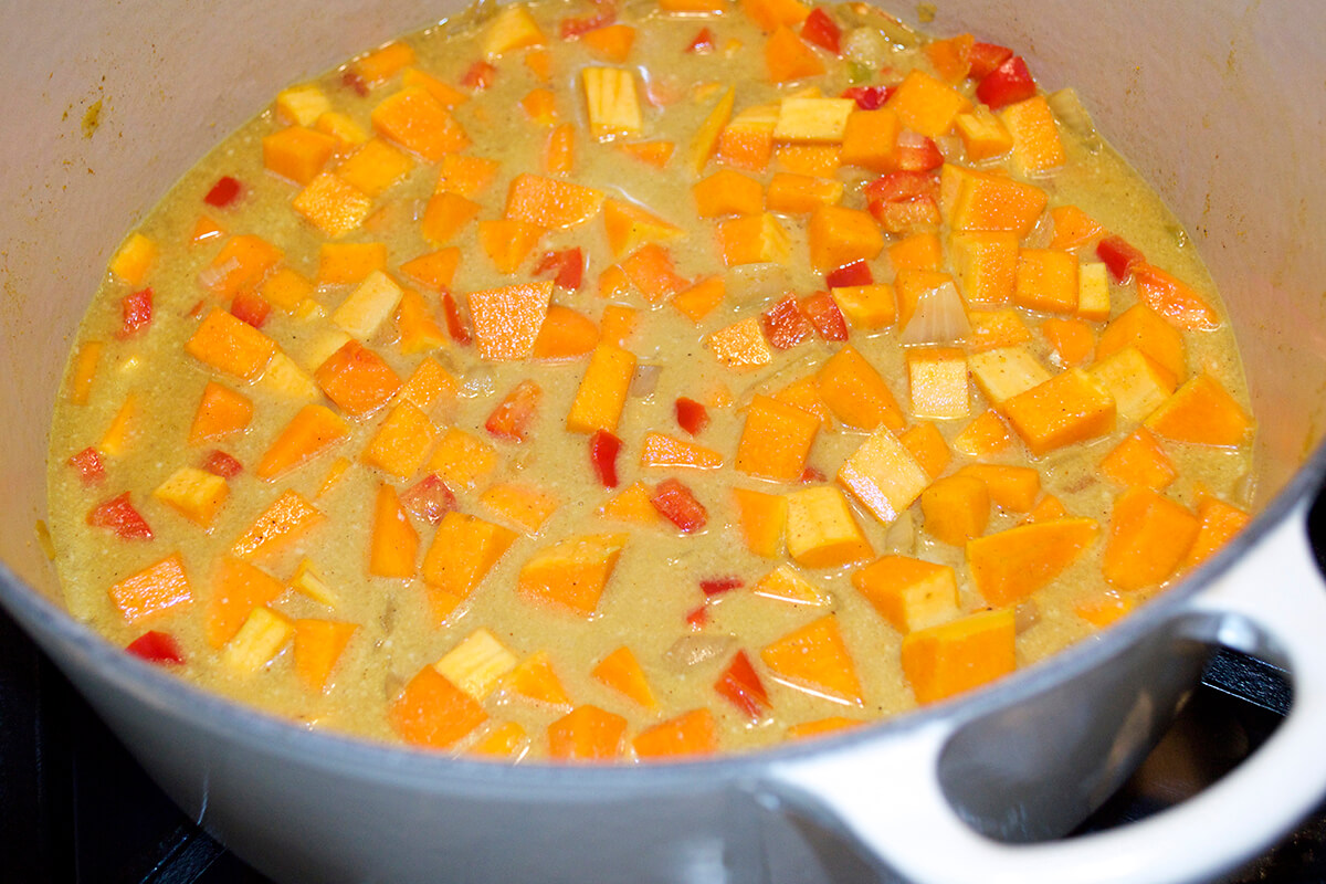 A saucepan of diced butternut squash, red pepper and curry sauce/stock