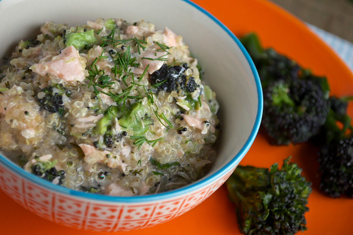 A bowl Salmon In A Creamy Lemon Dill Sauce with quinoa and purple sprouting broccoli next to some broccoli