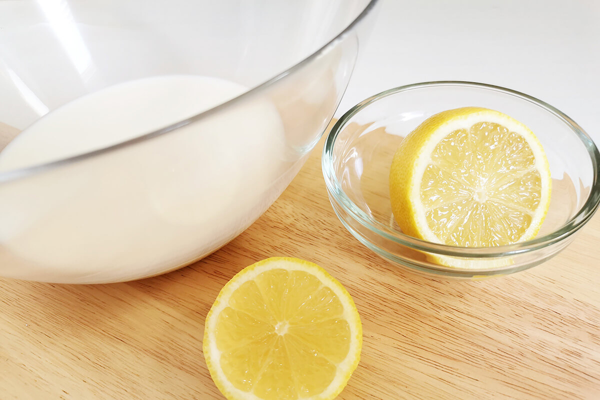 A bowl of milk next to a halved lemon