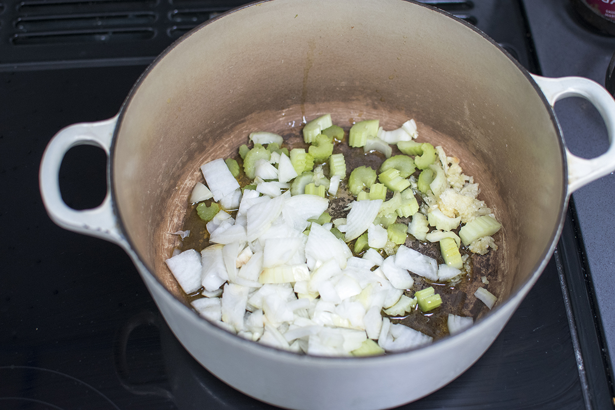 Onion, garlic, celery and potatoes being fried in a saucepan with oil