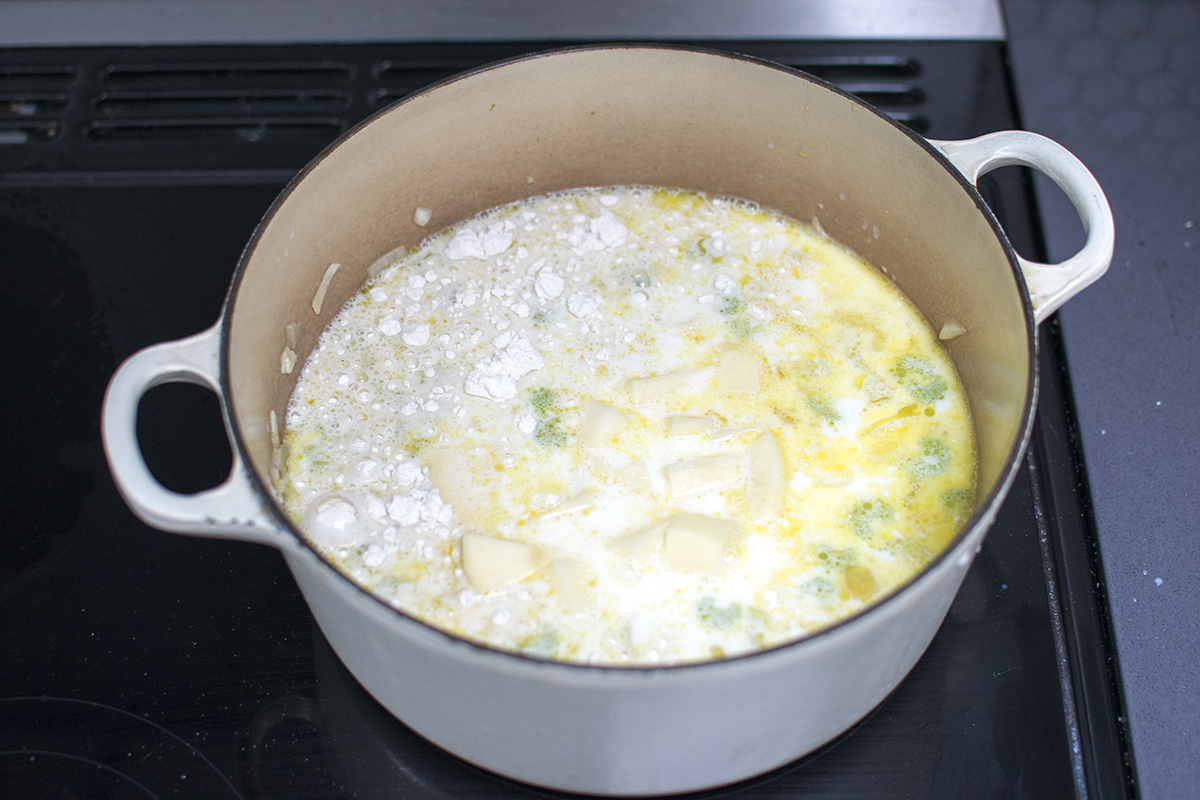 Saucepan with onion, garlic, celery and potatoes with added milk and flour