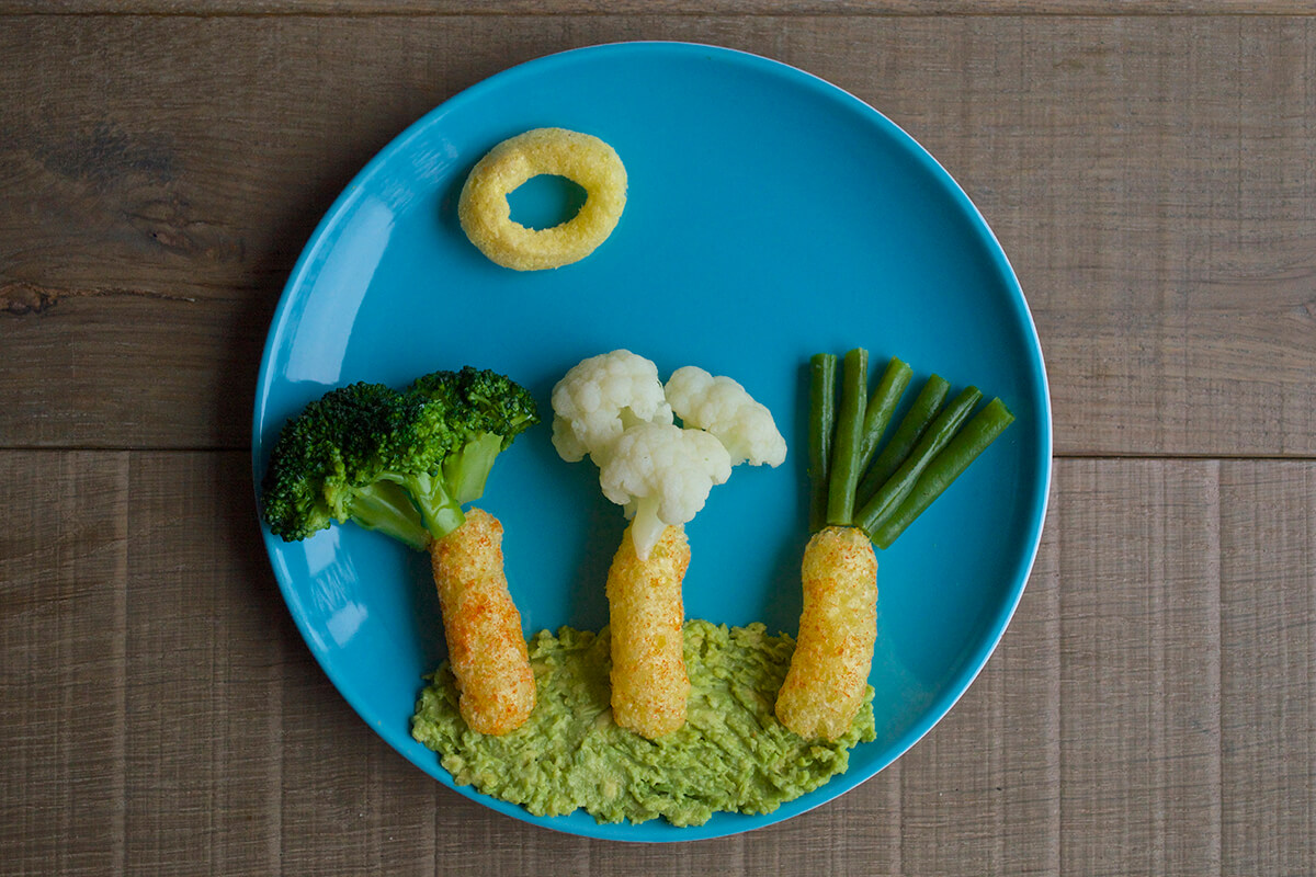To create the trees, the broccoli florets are placed above a melty carrot puff, the next carrot puff has the cauliflower florets above it and the last one green beans to complete the trees. The organix sweetcorn ring is placed above the trees to create the sun