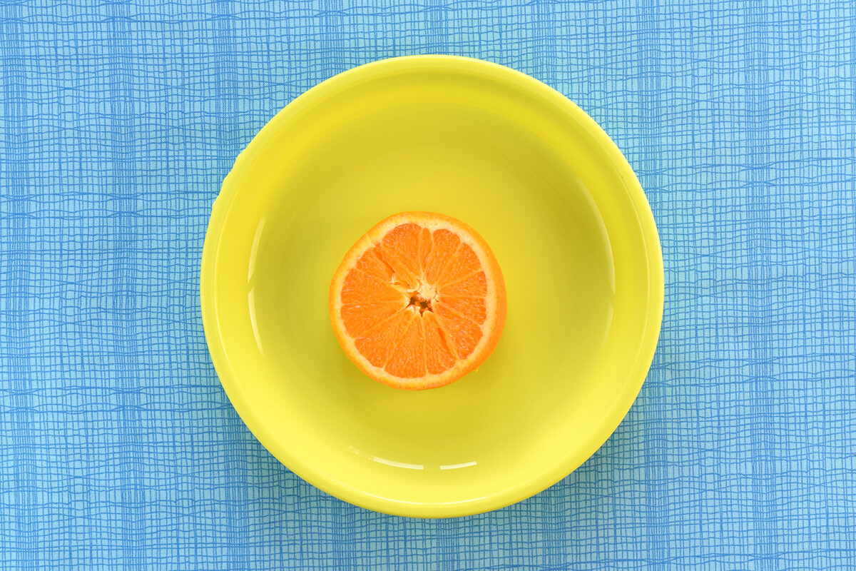 Two semi circles of orange placed in the middle of a plate and pushed together to form a circle