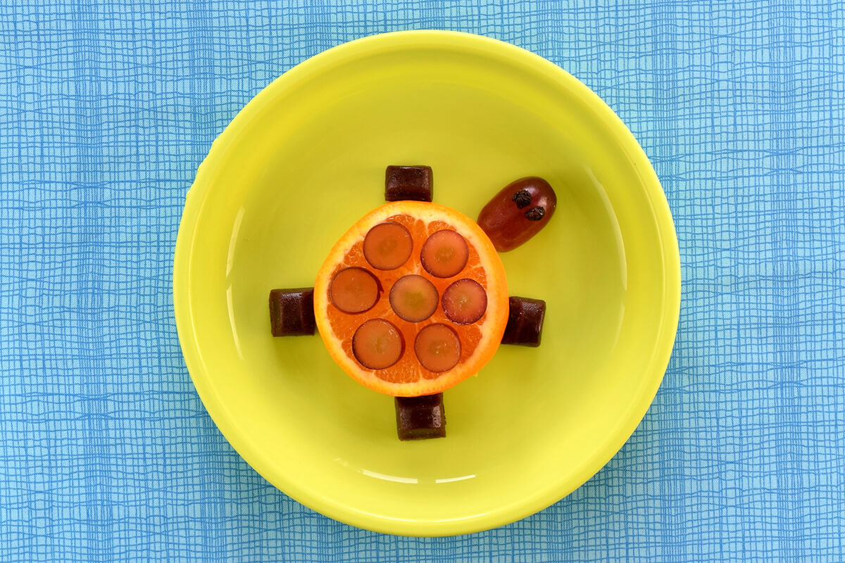 To finish off the turtle time fun plate, two halves of a raisin are placed on the grape to create the turtle's eyes