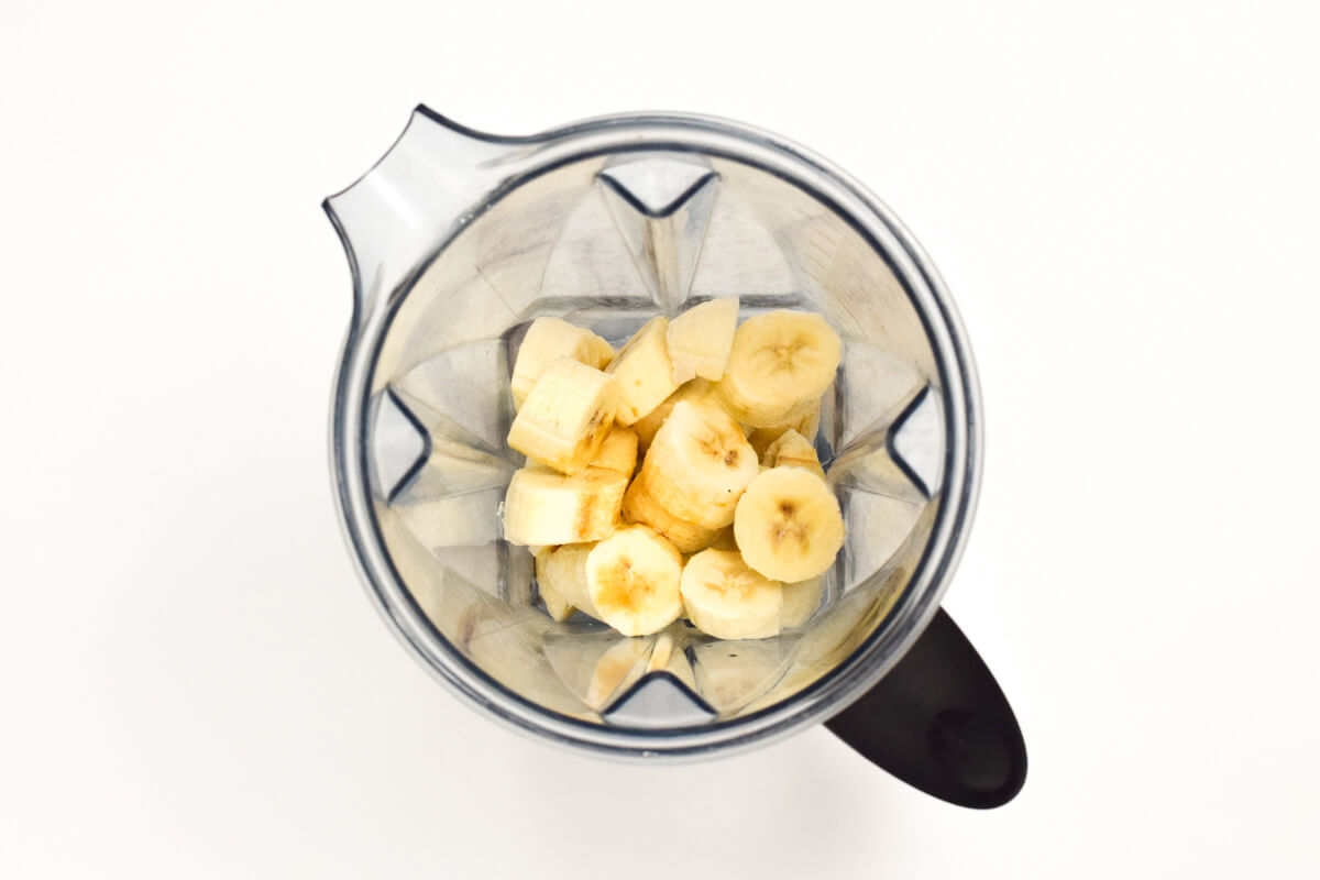 A food processor with frozen banana slices in it