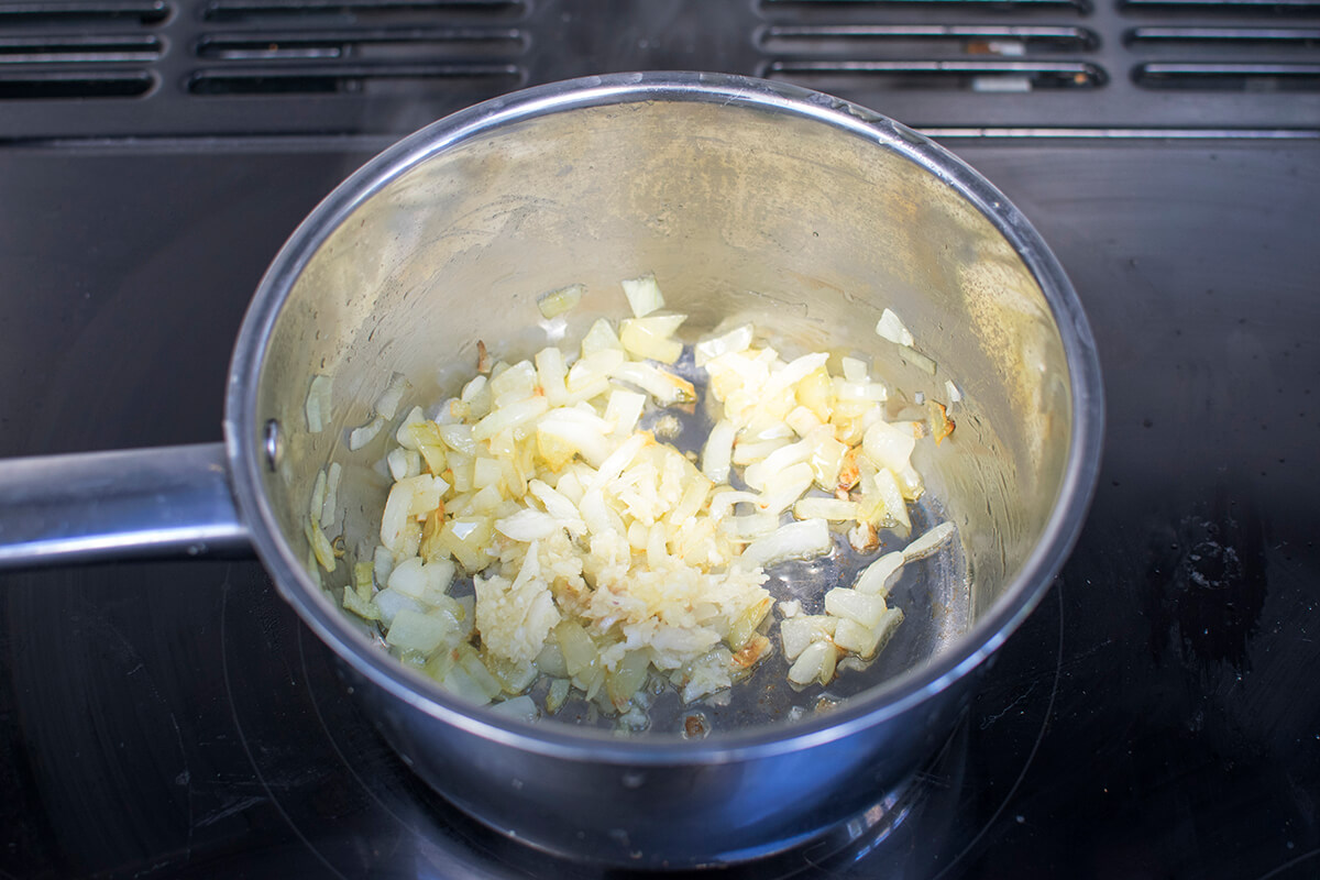 Chopped onion and garlic being fried in a saucepan