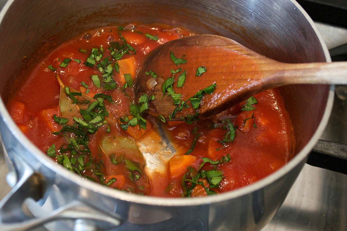 Onion, carrot, parsley, bay leaf and tomatoes simmering in water