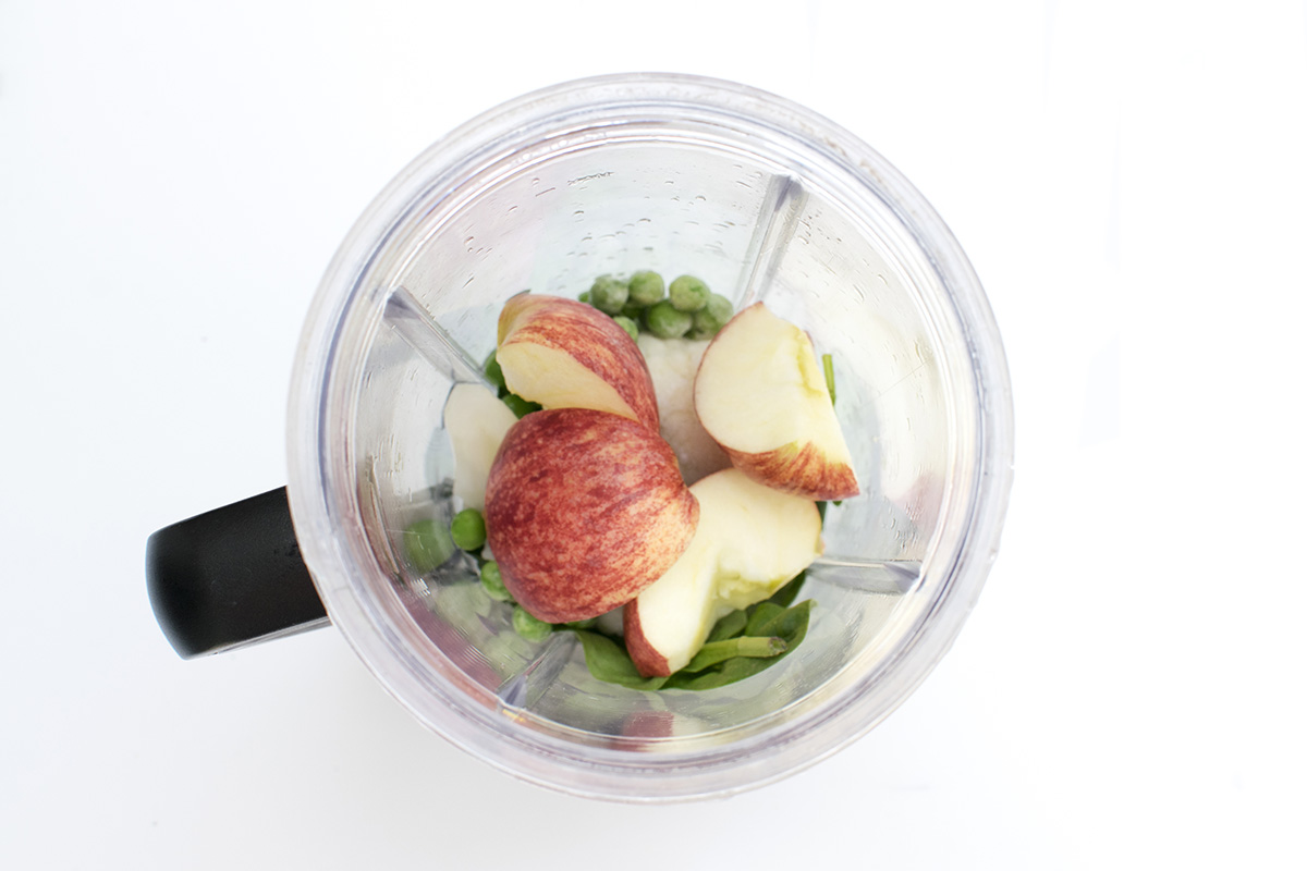 Sliced apple, cauliflower florets, peas and spinach in a blender