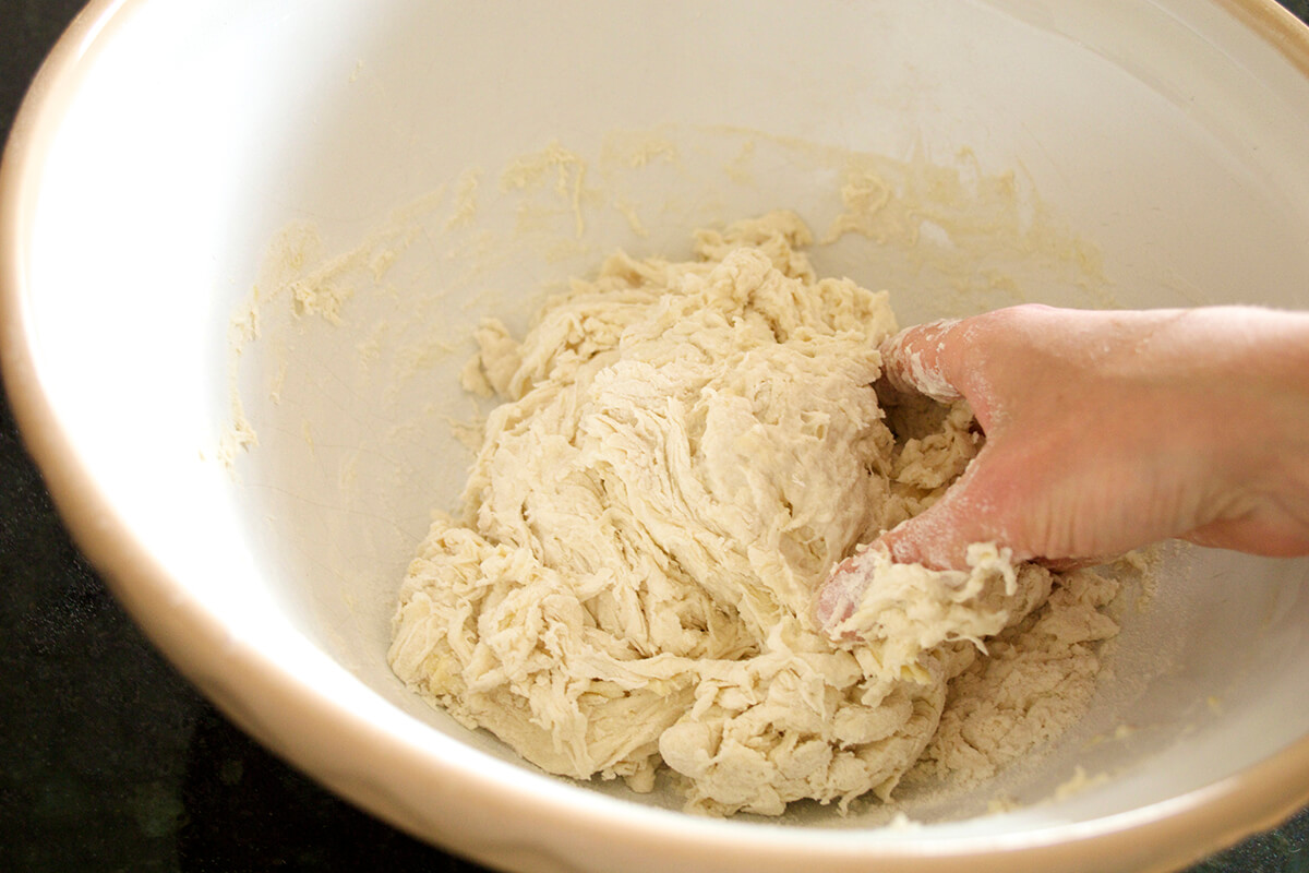 Bread dough being mixed by hand in a large bowl