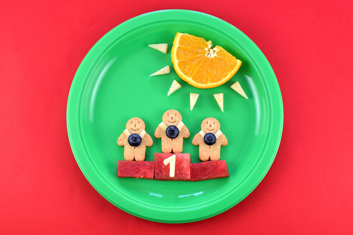 An apple cut into the shape of the number 1 is placed on the watermelon in the centre to complete the Winning Gingerbread Men Fun Plate
