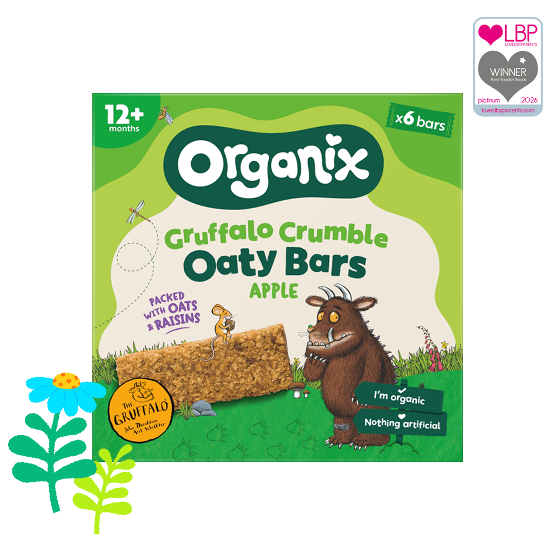 A green pack of Organix Gruffalo crumble Apple oaty bars with the Gruffalo character on the front. There is 1 blue flower and some green cartoon leaves are on the left