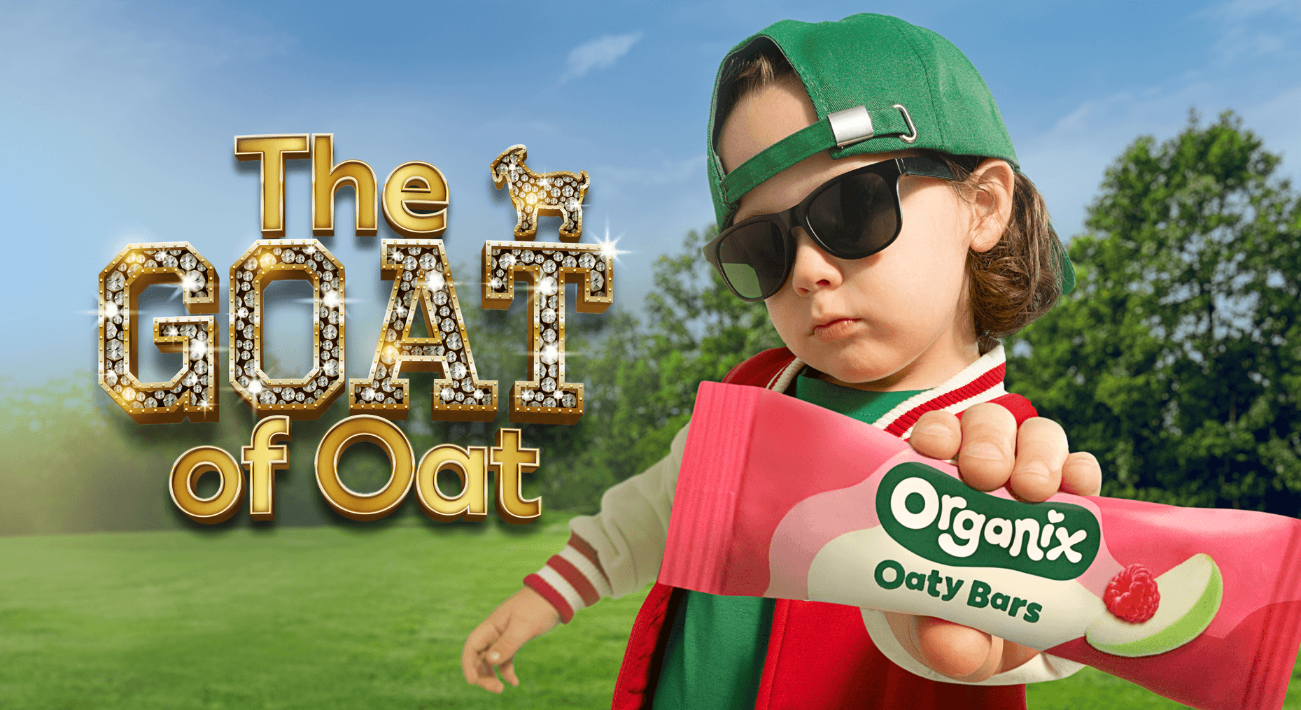 The goat of oat, toddler holding organix raspberry and apple oaty bar in backwards cap and sunglasses 