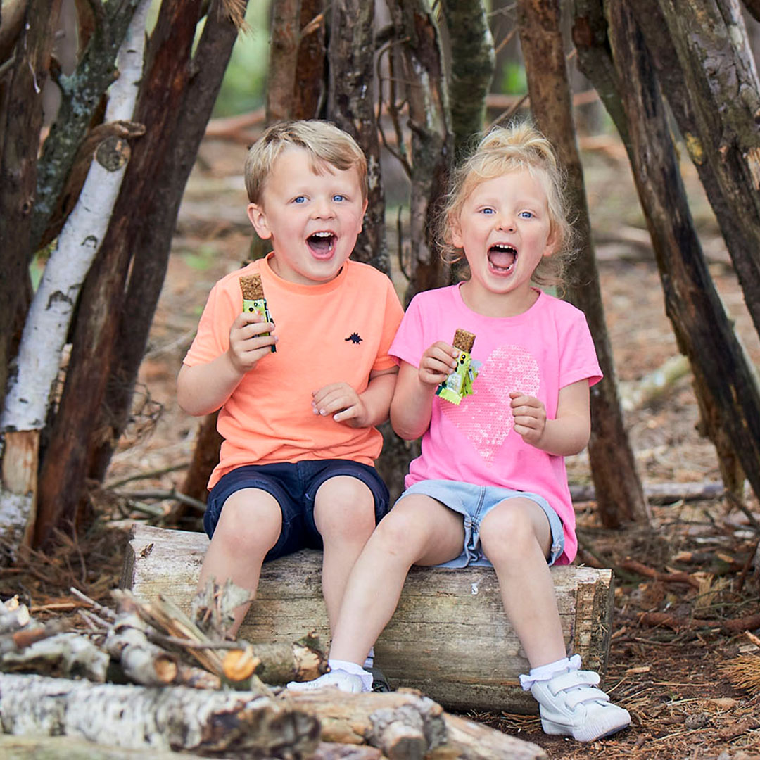 Two children, eating snacks in woodlands